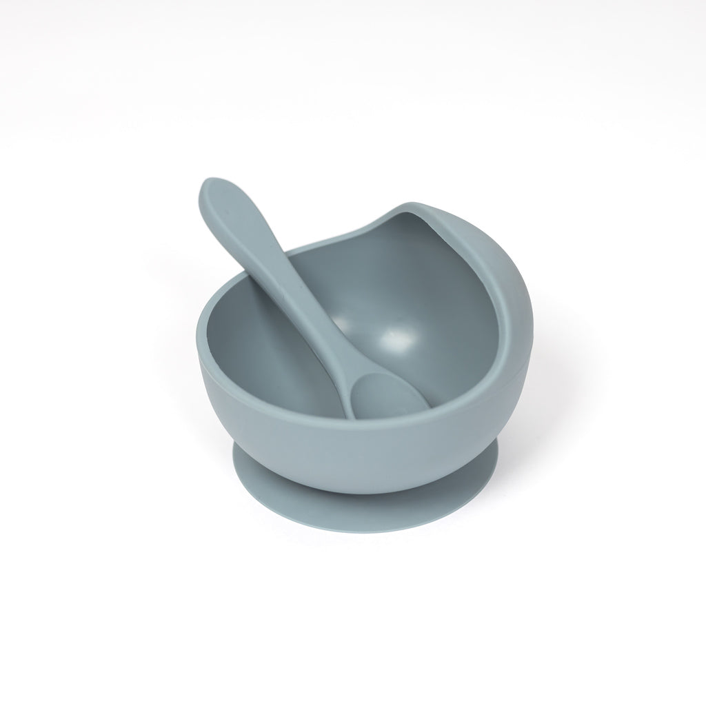 image of 100% food grade silicone bowl and spoon set. Toddler sized spoon sits in side of bowl and suction bowl features a curved lip to make scooping easy