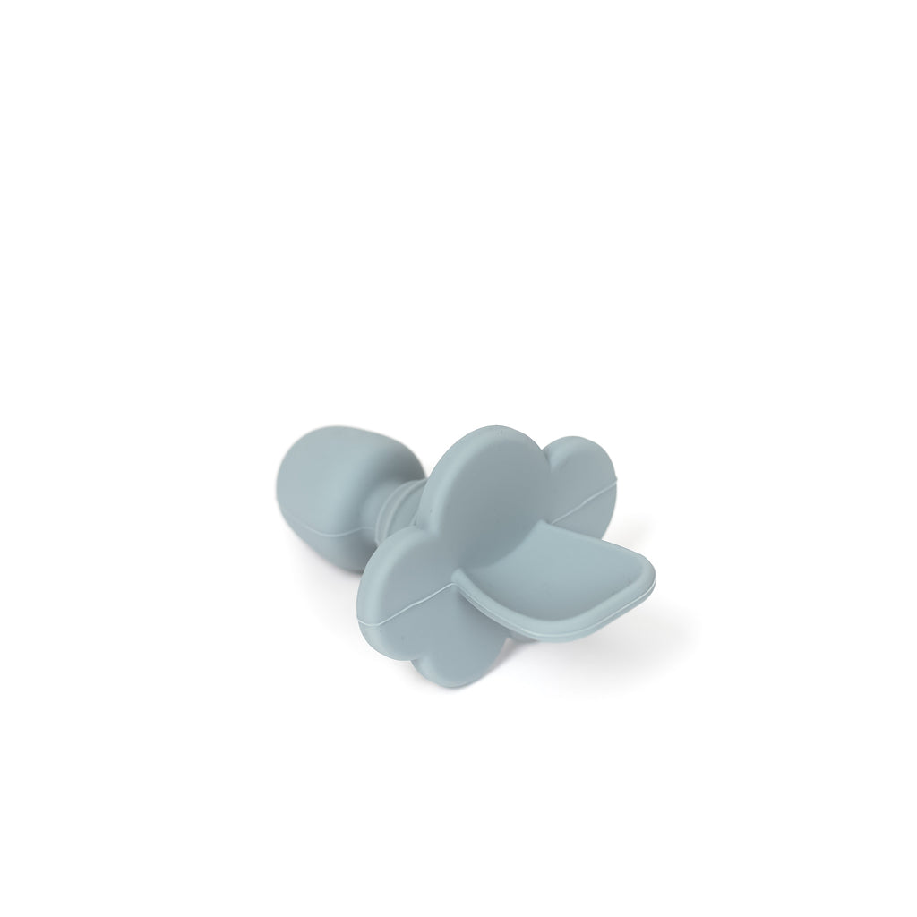 angled image of silicone toddler training spoon in pale blue. Spoon is made from 100% food grade silicone has a thick short handle to make holding easy and a cloud shaped stopper beneath the soft spoon lip to help prevent gagging as baby learns to eat
