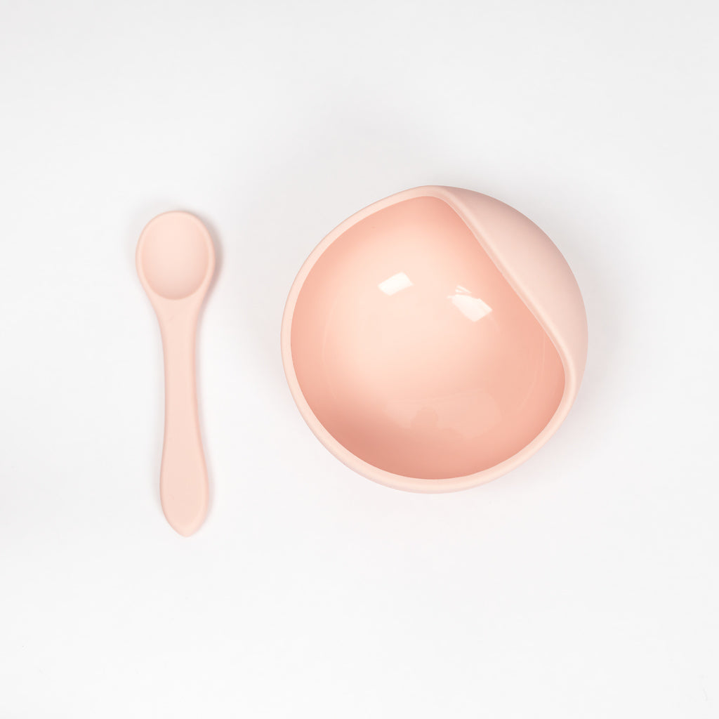 Silicone bowl and spoon set in blush pink on white background.
