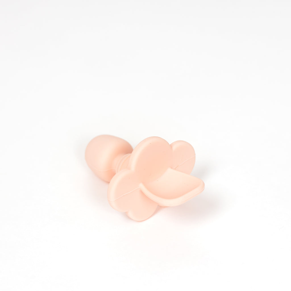 Toddler training spoon in blush pink on white background.