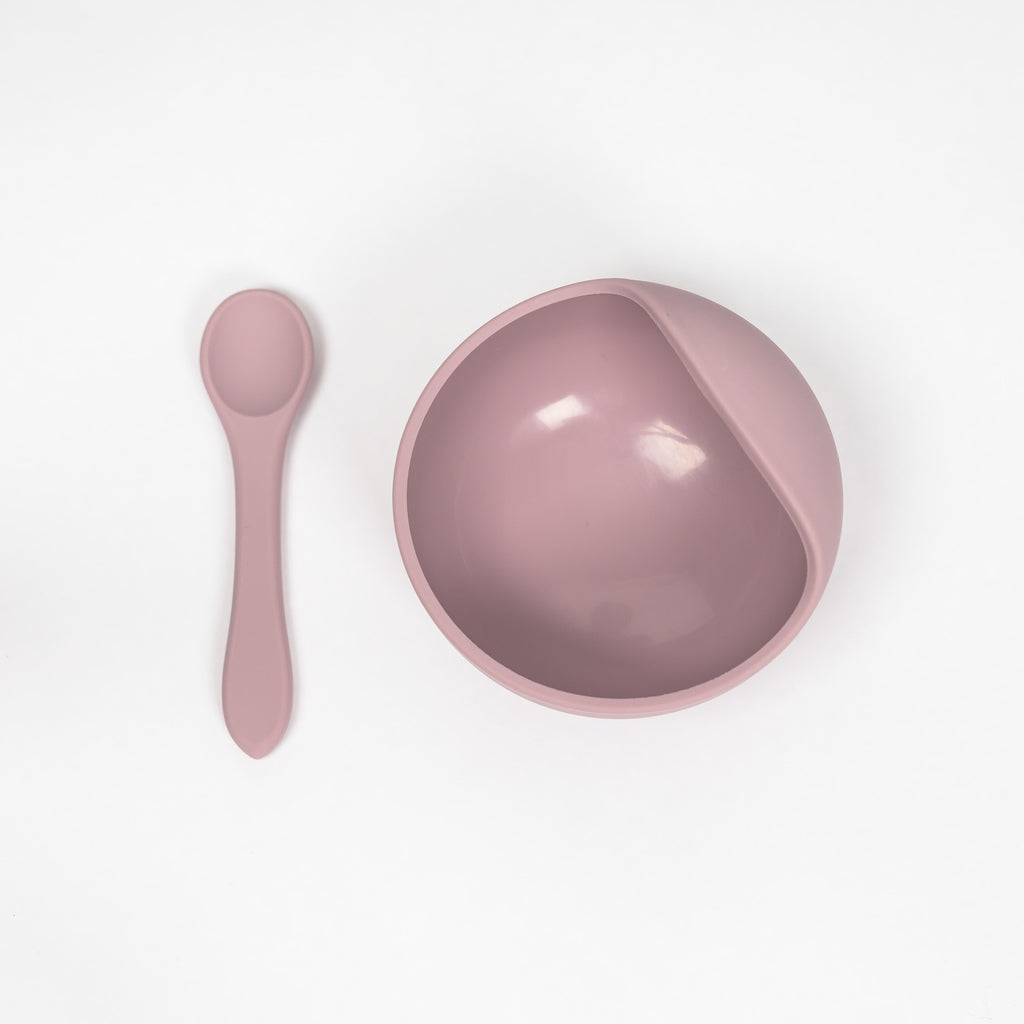 100% food grade silicone feeding set for toddlers. Image shows a suction bowl with curved lip to help with scooping purees and a toddler sized silicone spoon both in a pale mauve colour