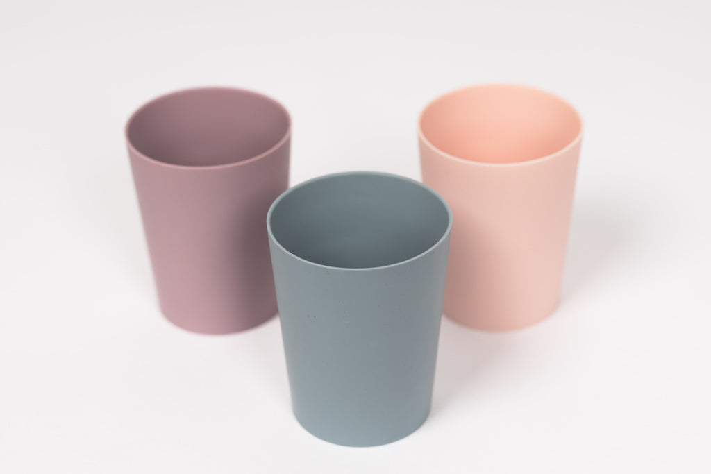 3 silicone toddler cups stand beside each other in blush, pale mauve and pale blue
