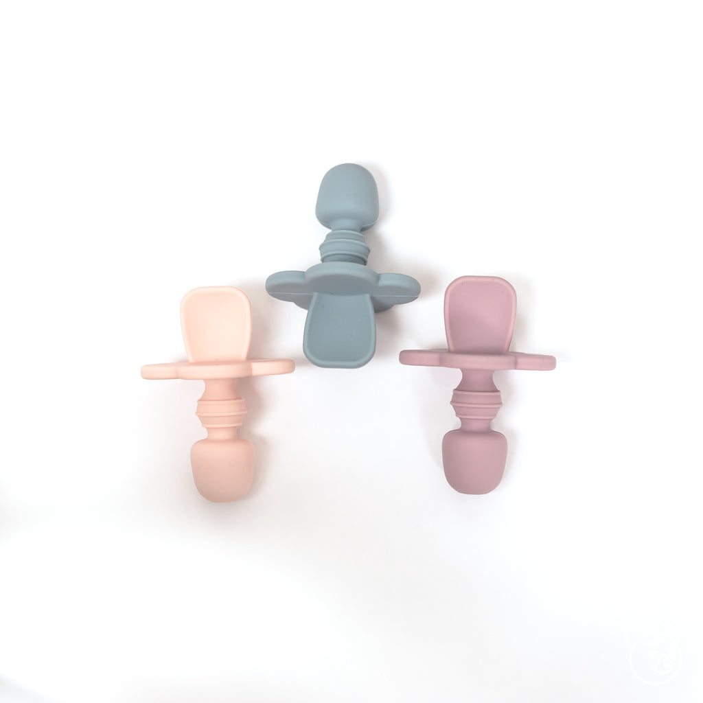 Image of three 100% food grade silicone infant training spoons in mauve pale blue and blush pink