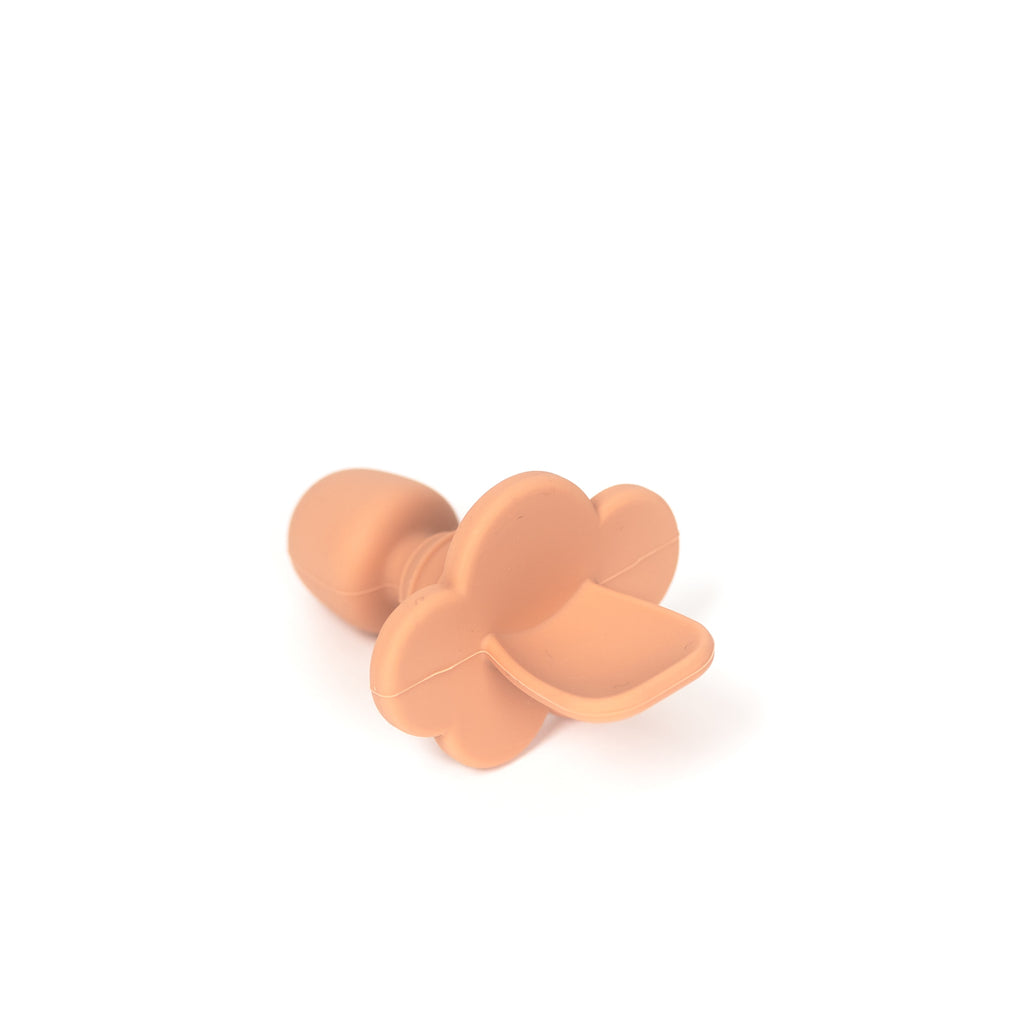angled image of silicone toddler training spoon in terracotta. Spoon is made from 100% food grade silicone has a thick short handle to make holding easy and a cloud shaped stopper beneath the soft spoon lip to help prevent gagging as baby learns to eat