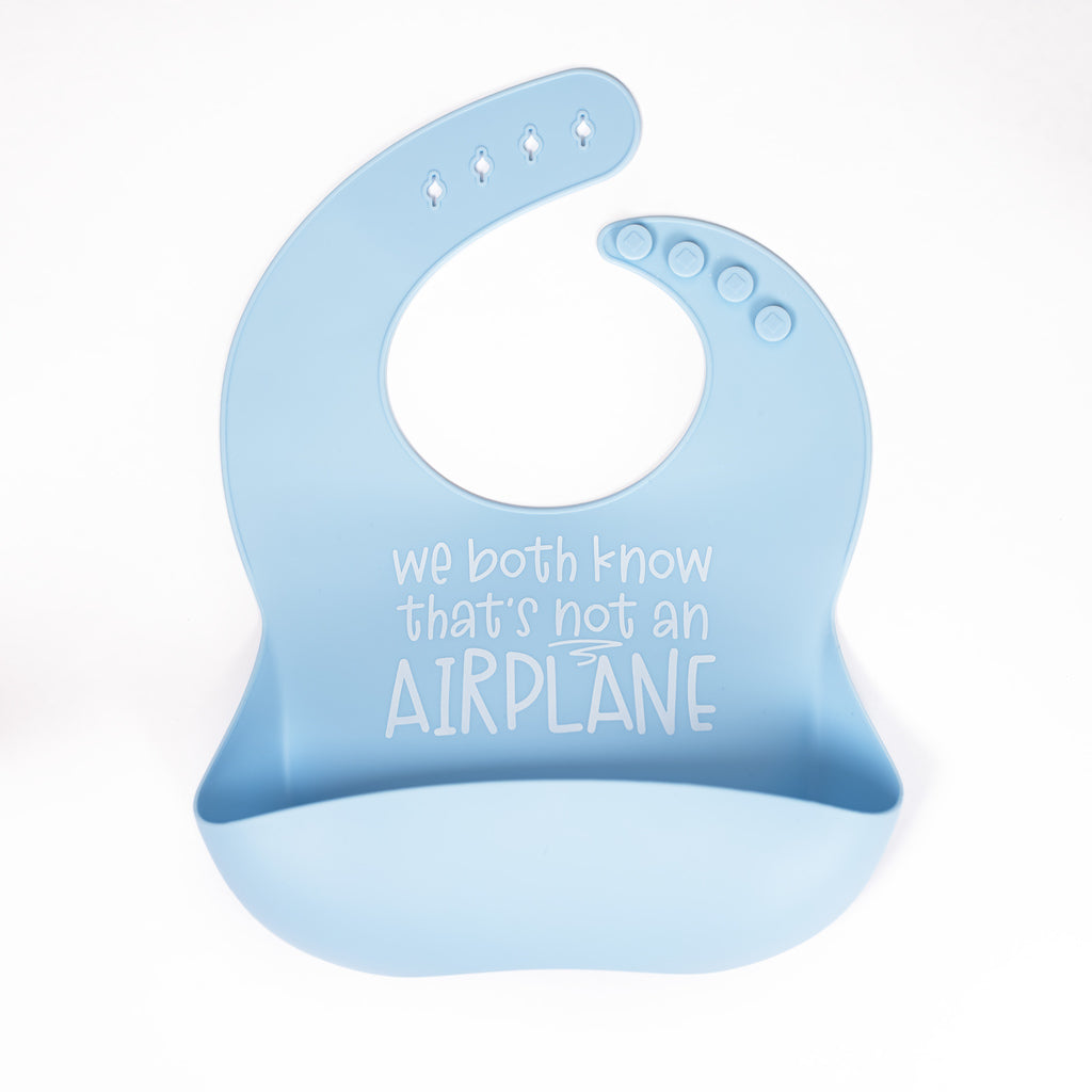 Light blue safety tested silicone bib with text we both know that's not an airplane in white text.