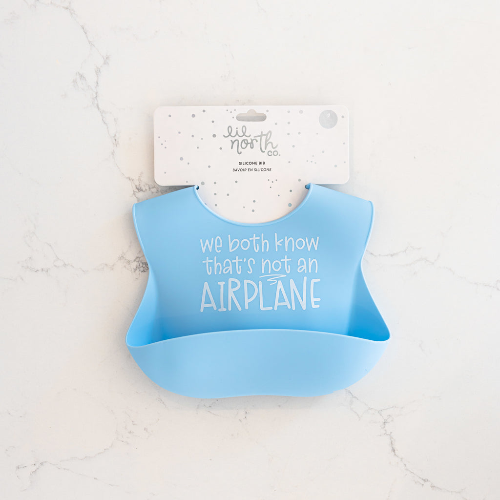 Light blue safety tested silicone bib with text we both know that's not an airplane in white text.