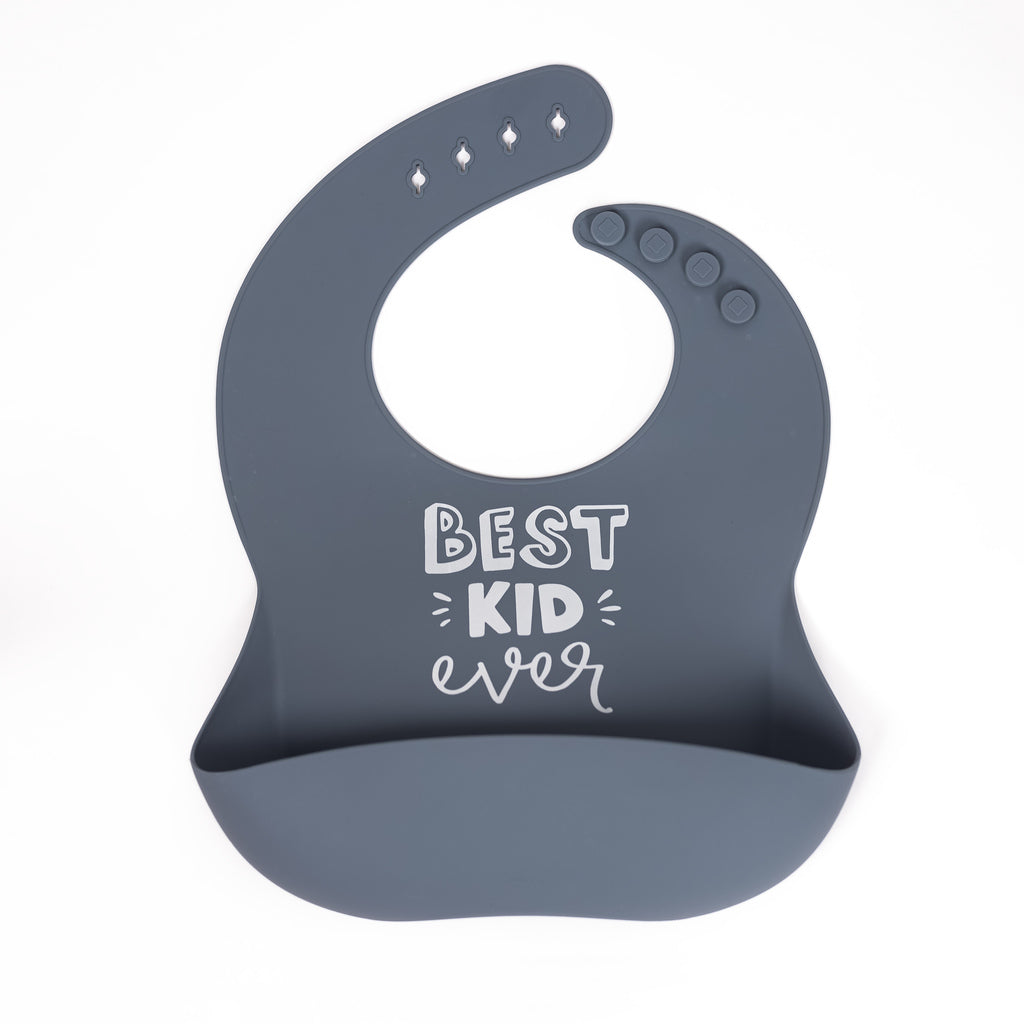 Safety tested silicone bib in slate blue with text best kid ever in fun white font.