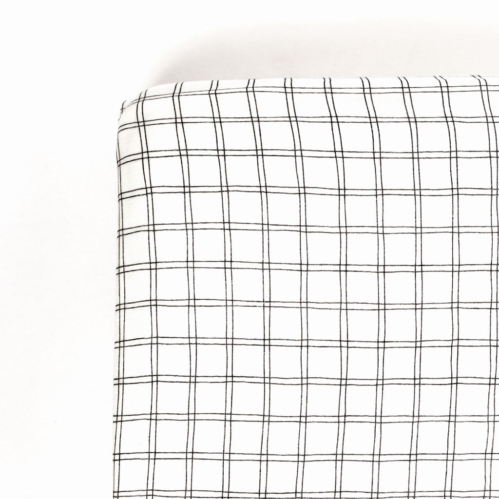 corner image of premium bamboo cotton muslin crib sheet with black and white grid print