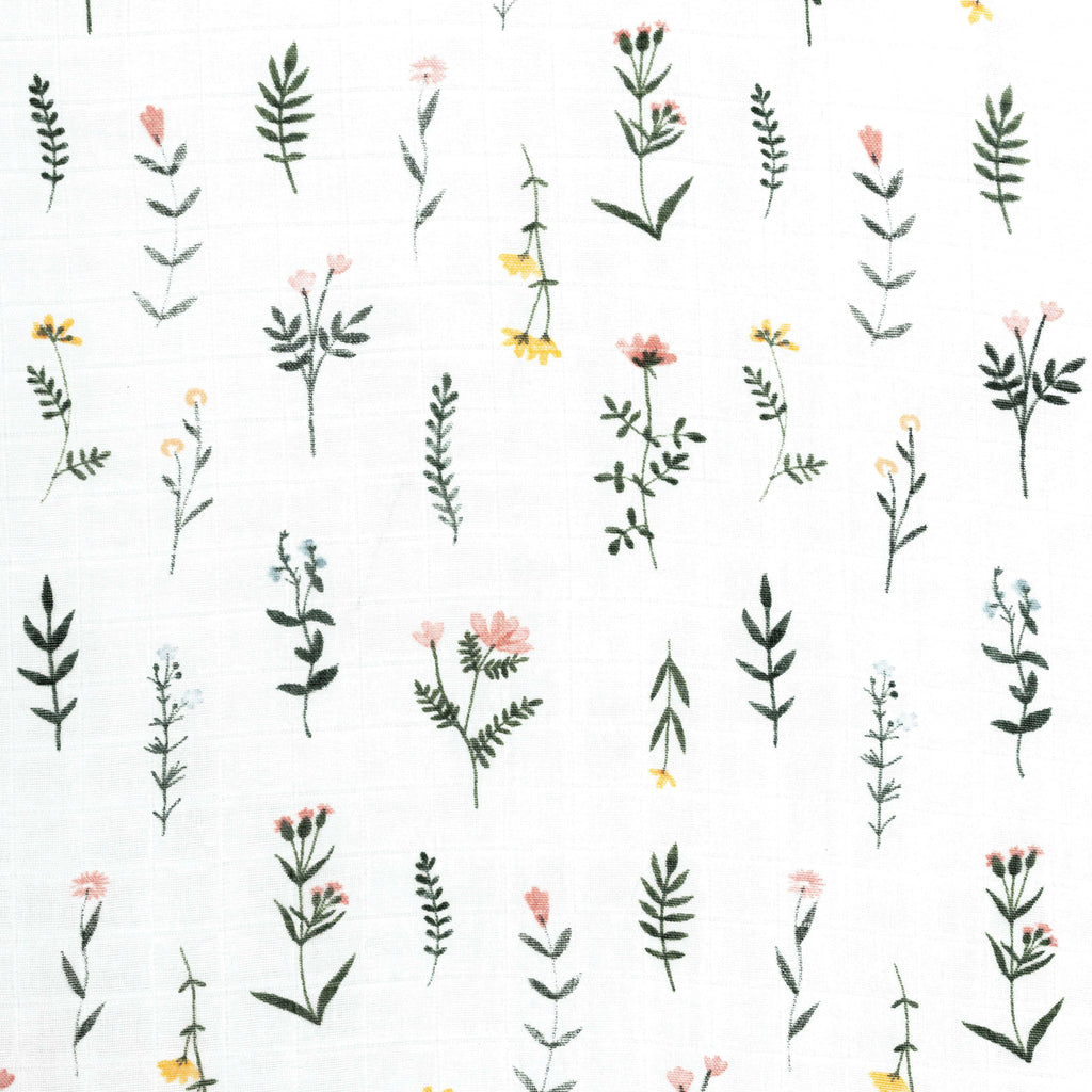 Closeup image of boho wildflower muslin crib sheet. Flowers are in various vertical placement with blush yellow and blue florals