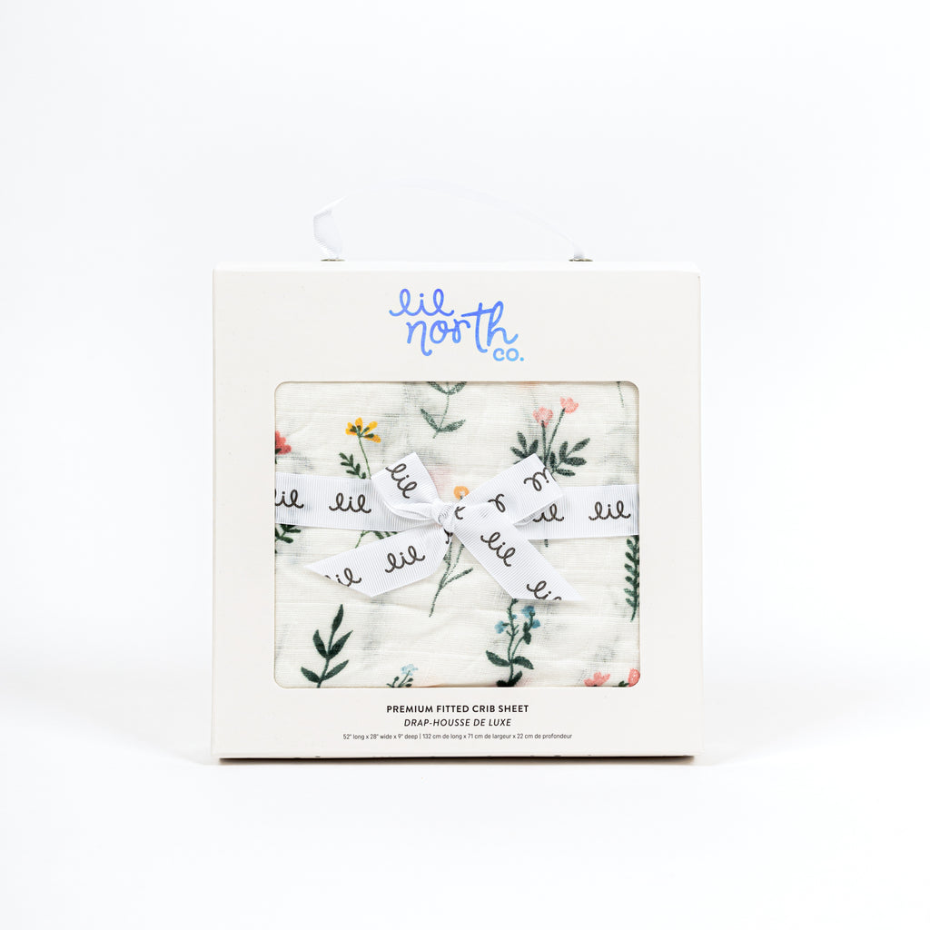 PErfectly boxed crib sheet. White box with lil north co logo and ribbon tied in a bow. florals are blush yellow and blue with green stems and leaves