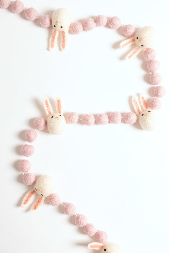 image of an easter bunny felt garland. the garland has felt blush balls strung between felt white bunny heads.