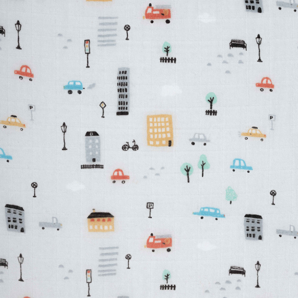 Close up image of city cars print. Grey background with buildings and street signs, blue red and yellow cars printed on bamboo cotton muslin 