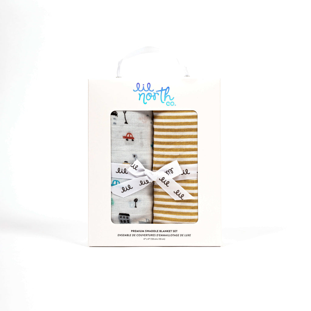 Perfectly boxed swaddle blanket set perfect for baby shower or newborn gift. white box with two swaddles, one ochre stripe and one city car print