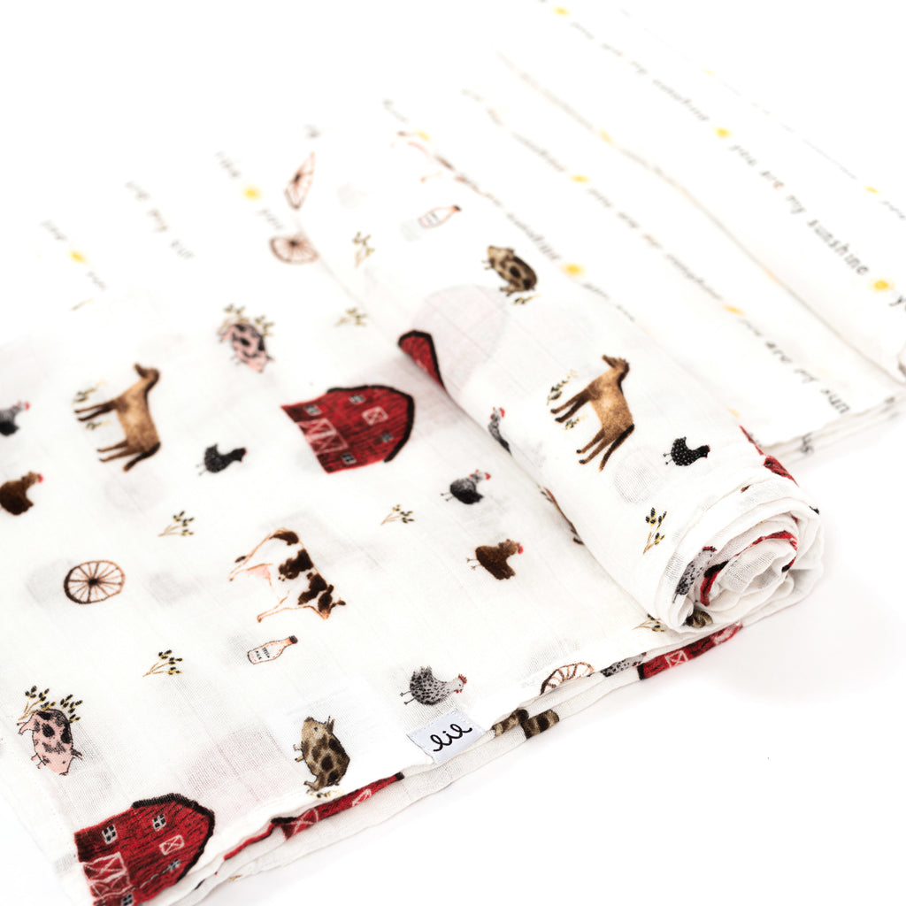 rolled swaddles featuring a farm animal print with red barn horses cow and chickens paired with a you are my sunshine typography print with a yellow sun between each phrase