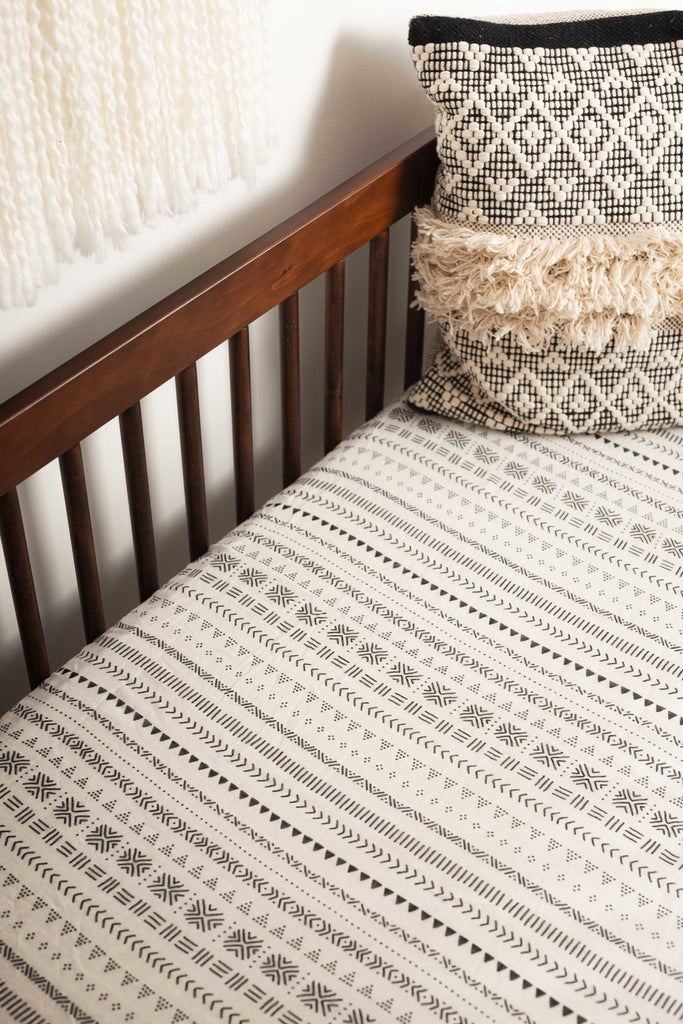 lifestyle image of black and white tribal crib sheet in walnut hudson babyletto crib