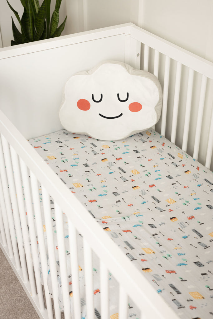 Lifestyle image of city cars grey and bright coloured crib sheet in white storkcraft crib styled with cloud pillow