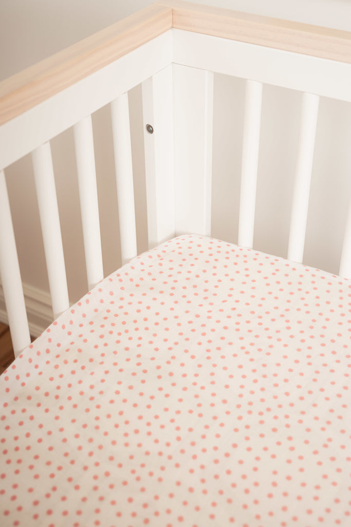 image of the corner of the scoot babyletto crib with lil north co blush dot muslin crib sheet