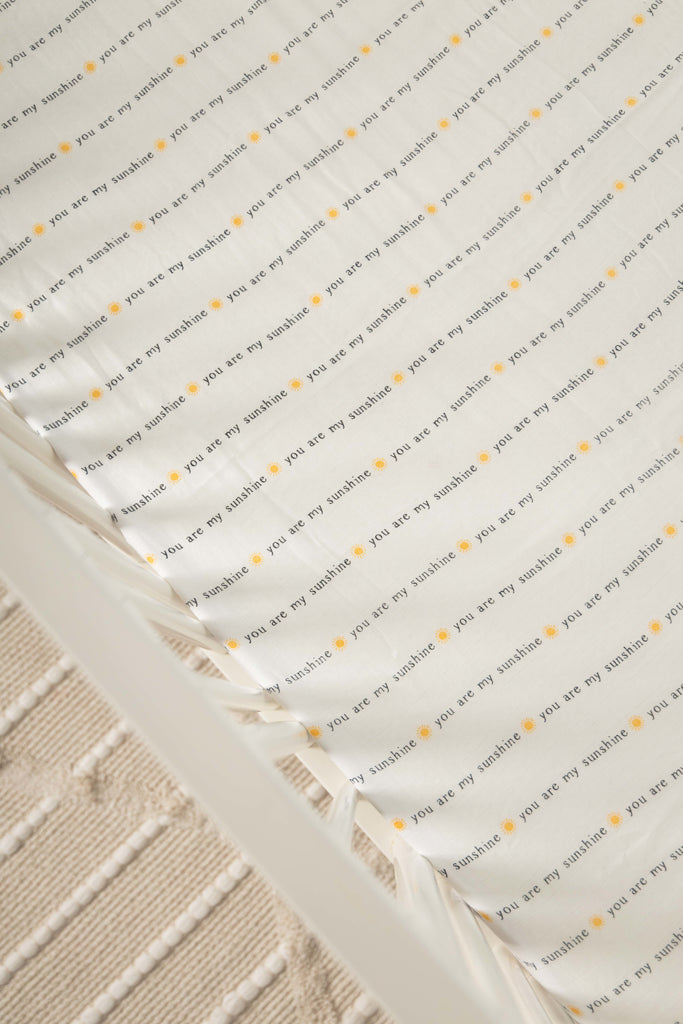 lifestyle image of you are my sunshine crib sheet in white crib