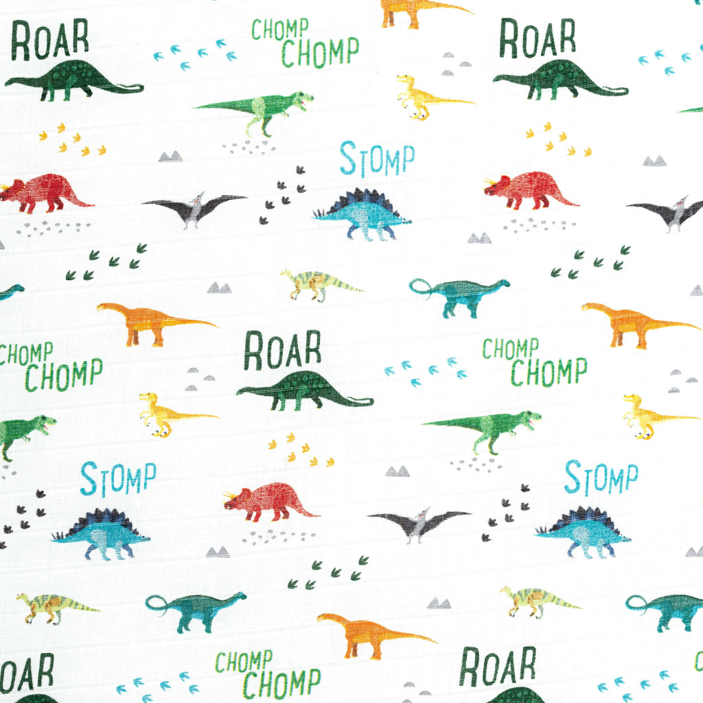 close up image of bright dino muslin crib sheet. Bright colours include greens red orange yellow and turquoise 