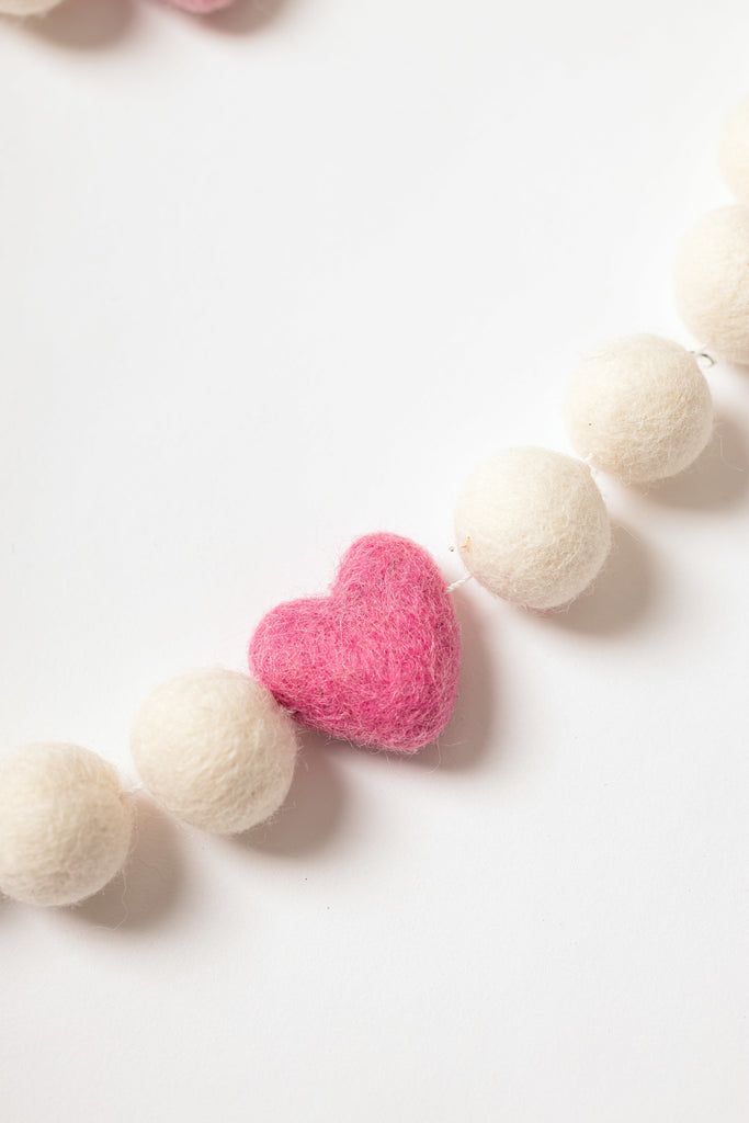 image of bright pink heart strung beside white felt balls