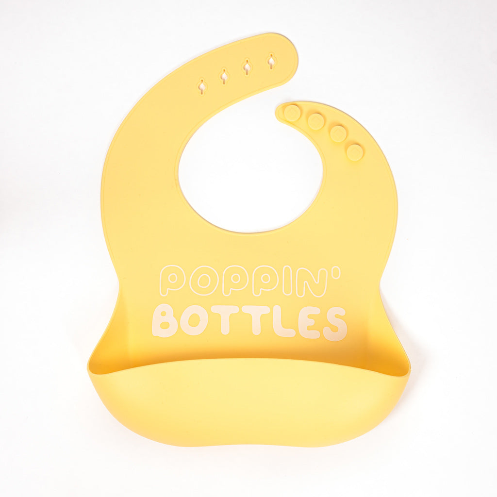 safety tested silicone bib in pale yellow with poppin bottles text in white shipping from canada
