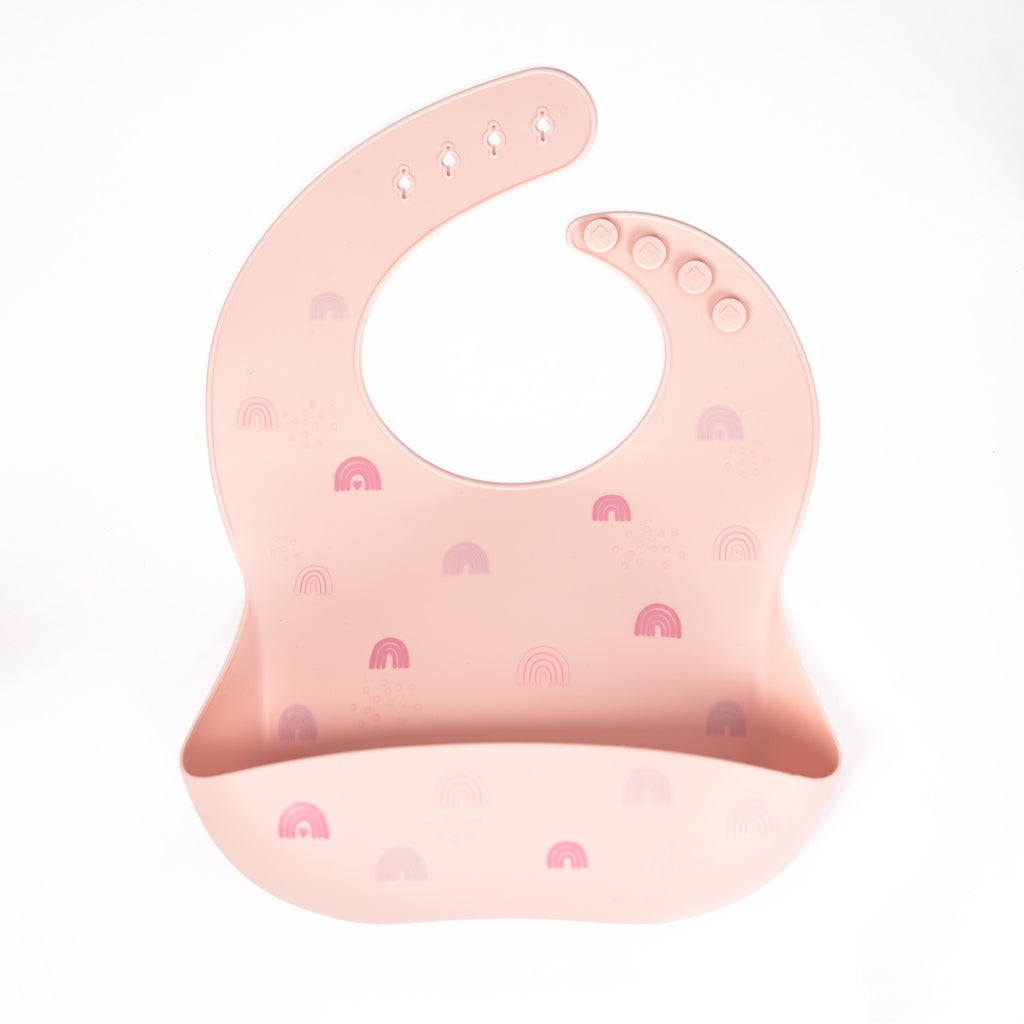 Safety tested silicone bib in blush with tossed rainbows in pink and purple tones.