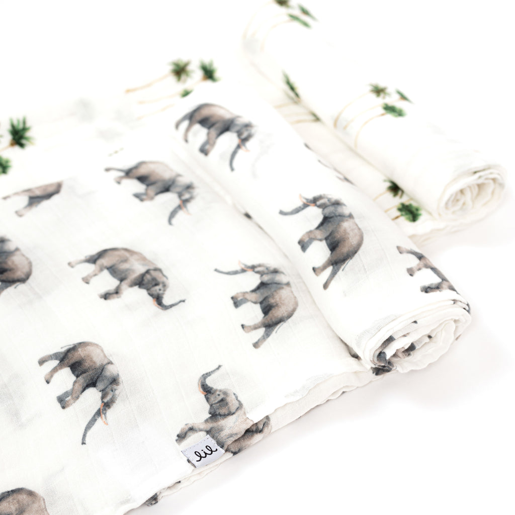 rolled lay flat premium bamboo cotton muslin swaddle blankets. Grey elephant paired with palm tree print both on white ground