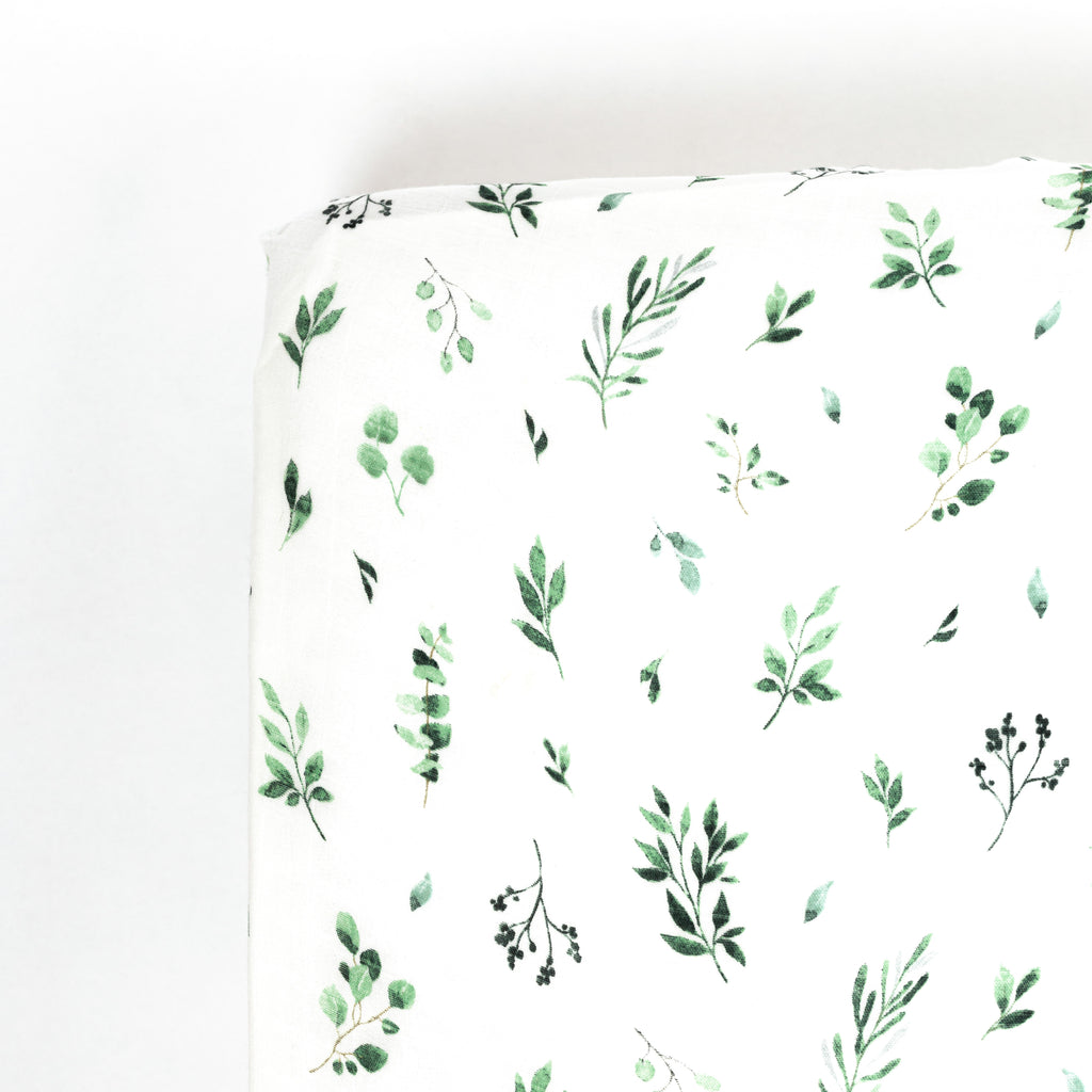 Corner image of green and sage watercolour foliage print on premium bamboo cotton muslin crib sheet