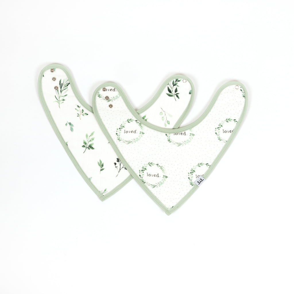 Set of two premium bamboo cotton muslin set of two bandana bibs including sage and green foliage print paired with loved font inside foliage wreath and soft dots in the bacground
