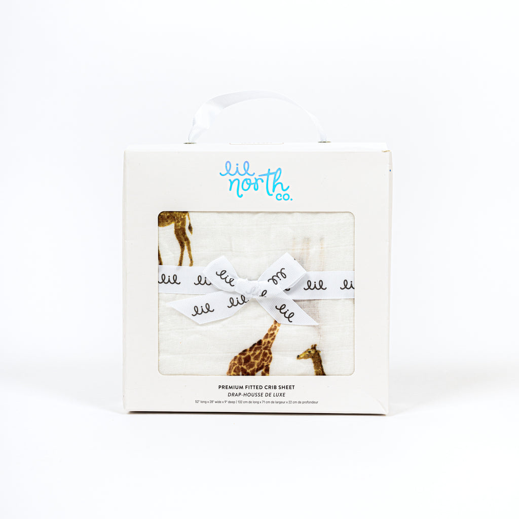 White box with white ribbon in a bow and lil north co label featuring giraffe bamboo cotton muslin crib sheet