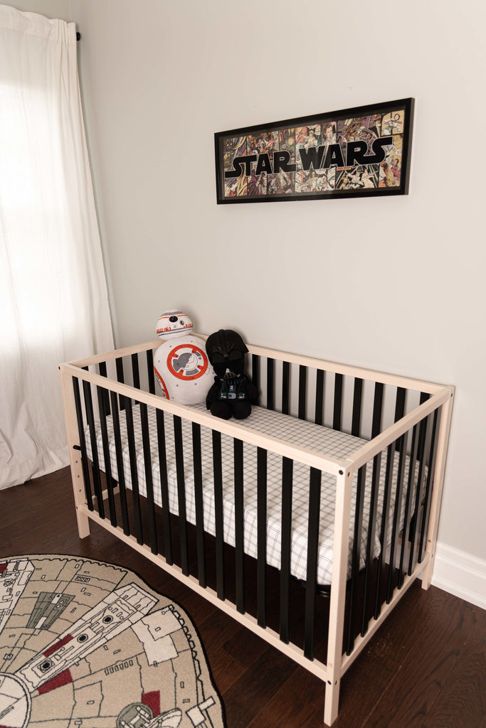 modern star wars nursery features black and natural wood crib with a black and white grid crib sheet
